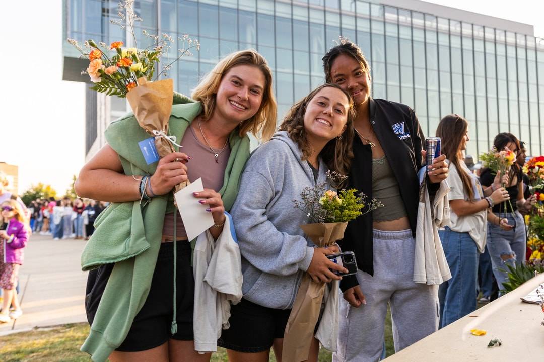 students smiling and holding flowers